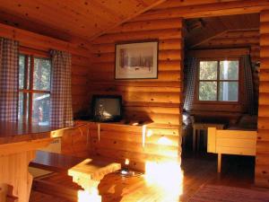 a living room of a log cabin with a television at Lomakylä Timitraniemi in Lieksa