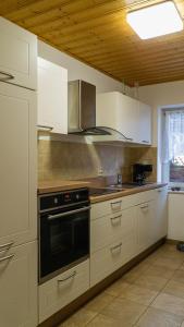una cocina con armarios blancos y horno negro en Ferienhaus am Osterberg en Quedlinburg
