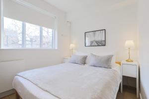 biała sypialnia z białym łóżkiem i oknem w obiekcie StayInn Soho Apartments w Londynie