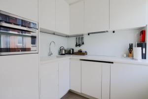 a white kitchen with white cabinets at StayInn Soho Apartments in London