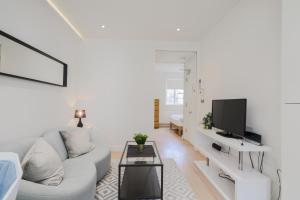 a white living room with a white couch and a tv at StayInn Soho Apartments in London