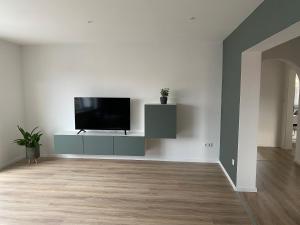 a living room with a flat screen tv on a white wall at Moderne Ferienwohnung Hergolshausen in Waigolshausen