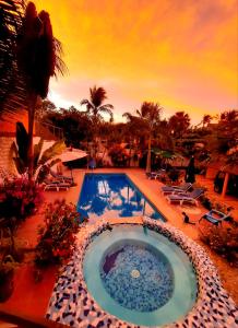 een zwembad met een zonsondergang op de achtergrond bij Hotelito Swiss Oasis -Solo Adultos - Adults only in Puerto Escondido