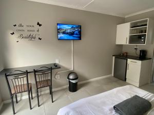 a bedroom with a bed and a tv on the wall at Gussella Lodge in East London