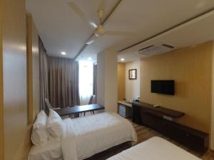 a hotel room with two beds and a television at Hotel Vdara in Vijayawāda