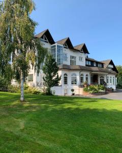 a large white house with a tree in the yard at Hotel Hammermühle in Wahlrod