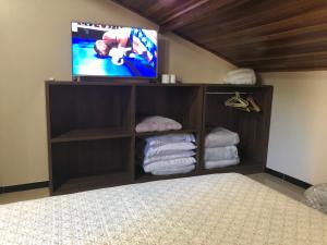 a bedroom with a bed with a tv and towels at Studio Julio Cezar in Foz do Iguaçu