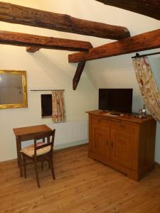 uma sala de estar com uma mesa, uma televisão e um armário de madeira em Hotel Ehinger Rose em Ehingen