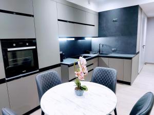 a kitchen with a white table and chairs and a table with a flower at AVENUE APARTMENTS-Hermes in Chişinău +82 photos