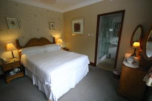 a bedroom with a large white bed and a shower at Three Horseshoes Country Inn in Leek