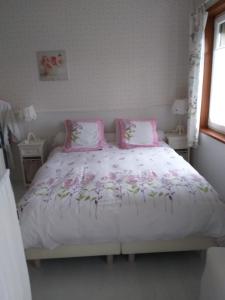 um quarto com uma cama com almofadas cor-de-rosa em B&B Au fil des saisons sur la Wiels em Fauvillers