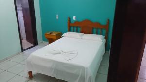 a bedroom with a white bed with a bow on it at Bravo City Hotel Nova Mutum in Nova Mutum