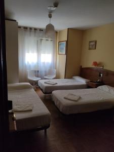 a hotel room with three beds and a table and chairs at Hotel Camagüey in Gijón