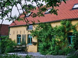 a yellow house with a red roof and chairs at Holiday Home Les Plachettes in Flobecq