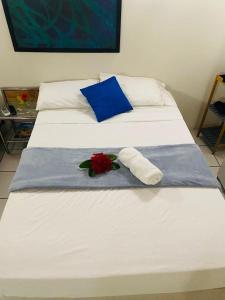 Una cama blanca con una almohada azul y una rosa. en Courtesy Apartments Aruba en Oranjestad