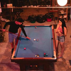 El Zoo Hostel, Bar & Pool في بالومينو: a man and a woman playing a game of pool