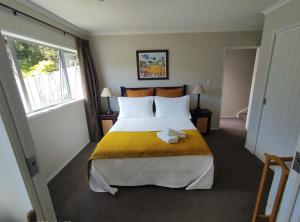 um quarto com uma cama grande e um cobertor amarelo em Castor Bay Homestay em Auckland