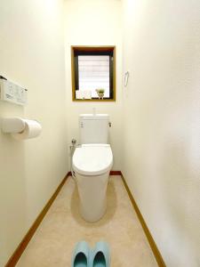 W łazience znajduje się toaleta z oknem i niebieskie kapcie. w obiekcie White Space w mieście Kakegawa