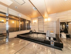 ein Badezimmer mit einer Badewanne und einer Uhr an der Wand in der Unterkunft APA Hotel Osaka Temmabashi-Ekimae in Osaka
