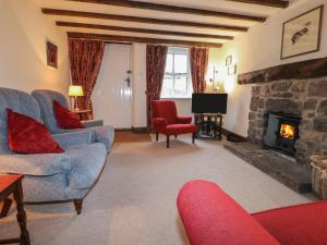 a living room with couches and a stone fireplace at Walton Cottage in Winster