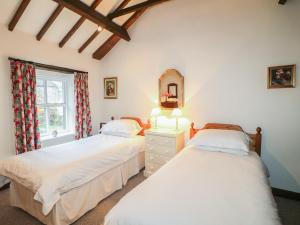 a bedroom with two beds and a mirror and a window at Walton Cottage in Winster