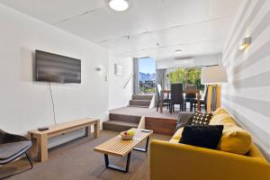 a living room with a yellow couch and a tv at Heart of Queenstown in Queenstown