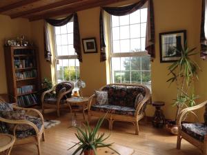 a living room with chairs and a table and windows at Admiralty House in Moville