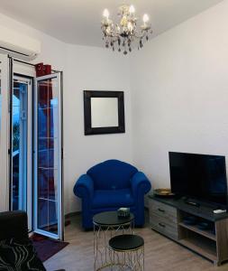 sala de estar con silla azul y TV en Almira sea view Appartment en Istron