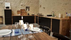a wooden table with wine glasses and a kitchen at Le clos des abeilles in Ruch