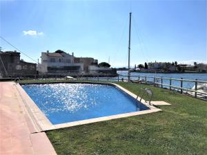 een groot zwembad naast een waterlichaam bij Apartamento en Roses con vistas al canal y piscina in Roses