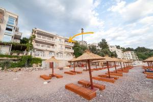 a beach with many chairs and umbrellas and buildings at Beachfront First Line View in Sveti Stefan