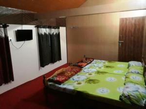 a bedroom with a bed with a green blanket at RAOJI Home Stay in Vālpārai +4 photos