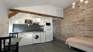 une cuisine avec un lave-linge et un mur en briques dans l'établissement Domaine Ravy-Azalée, à Saint-Symphorien-sur-Saône