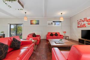 ein Wohnzimmer mit roten Sofas und einem Tisch in der Unterkunft Spacious 4 Bdrms near Murray River, Pet Friendly in Strathmerton