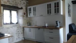 a kitchen with white cabinets and a sink and a window at LOU CHASTEL, DEMEURE PERIGOURDINE CLIMATISEE avec PISCINE PRIVEE et CHAUFFEE in La Bachellerie