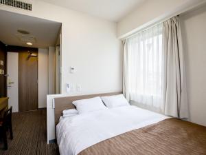 - une chambre avec un grand lit blanc et une fenêtre dans l'établissement Hotel Wing International Hitachi, à Hitachi