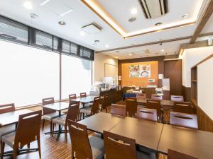 a restaurant with tables and chairs and a large window at Hotel Wing International Hitachi in Hitachi