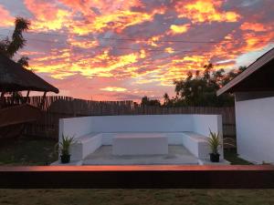 a sunset over a white bench in a backyard at Paradise Beach Guest House in Bantayan Island