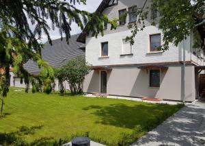 une maison blanche avec une pelouse devant dans l'établissement IZERSKA ZATOKA, à Stara Kamienica