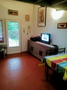 a living room with a television on a dresser and a door at Tres agreable maison au calme dans la pinede in Lacanau-Océan