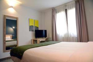 une chambre d'hôtel avec un lit et une télévision dans l'établissement Hotel Vijanera, à Galizano