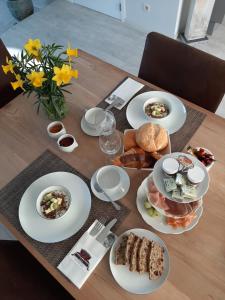 a wooden table with white plates of food on it at B&B Cosiness in Balen