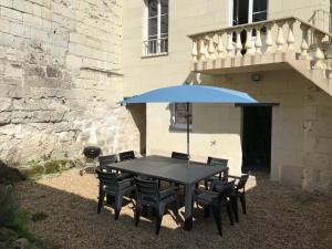 une table noire avec des chaises et un parapluie bleu dans l'établissement Jolie maison en tuffeau dans le centre de Saumur, à Saumur