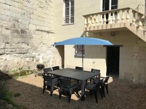 a black table with chairs and a blue umbrella at Jolie maison tuffeau centre de Saumur avec local vélos in Saumur