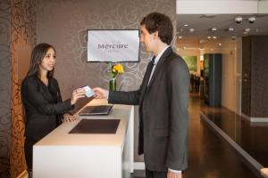 a man and a woman standing next to a counter at Mercure Montevideo Punta Carretas in Montevideo