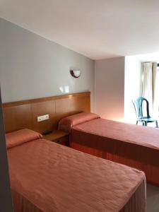 una habitación de hotel con 2 camas y una silla en DUPLEX JUNTO AL MAR, en Oia