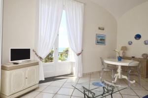 ein Wohnzimmer mit einem TV, einem Tisch und einem Fenster in der Unterkunft L'Ancora Amalfi Dreams in Minori