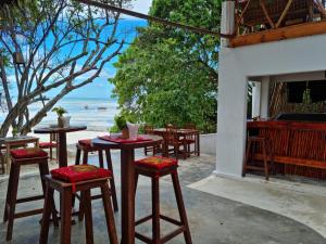 a group of tables and stools with a view of the ocean at Red Monkey Beach Lodge in Jambiani