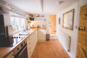 a kitchen with white cabinets and a wooden floor at Hectors house in Ormesby Saint Michael