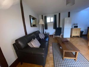 a living room with a black leather couch and a table at Low Farm Cottages in Woodbridge